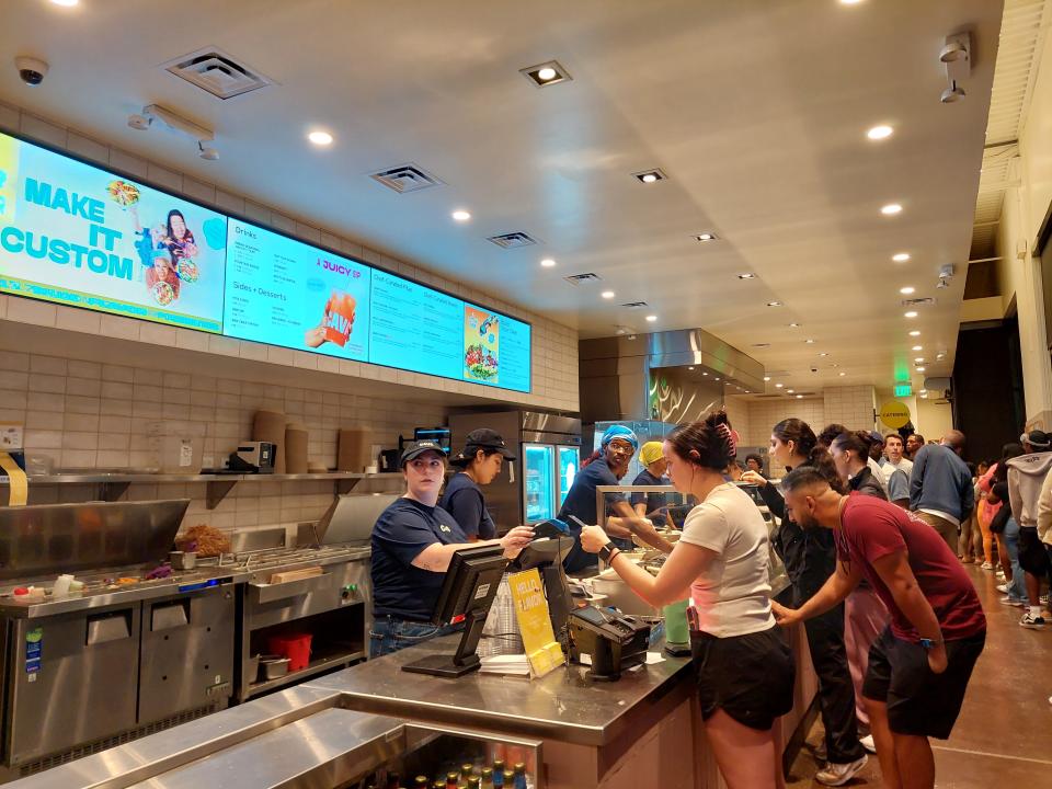 The interior of the Cava restaurant in Chicago, showing a customer paying at the counter