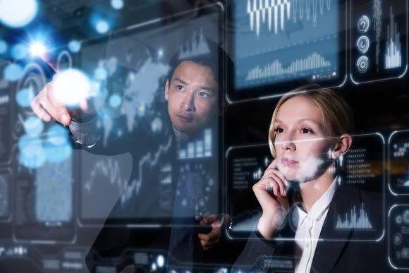 Two business persons in front of futuristic graphic display.