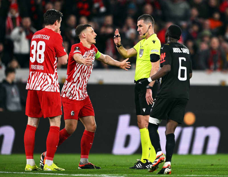 Freiburg players Michael Gregoritsch (L) and Maximilian Eggestein (2nd L) discuss with the Slovenian referee Rade Obrenovic (2nd R) during the UEFA Europa League soccer match between SC Freiburg and RC Lens at Europa-Park Stadium. Harry Langer/dpa
