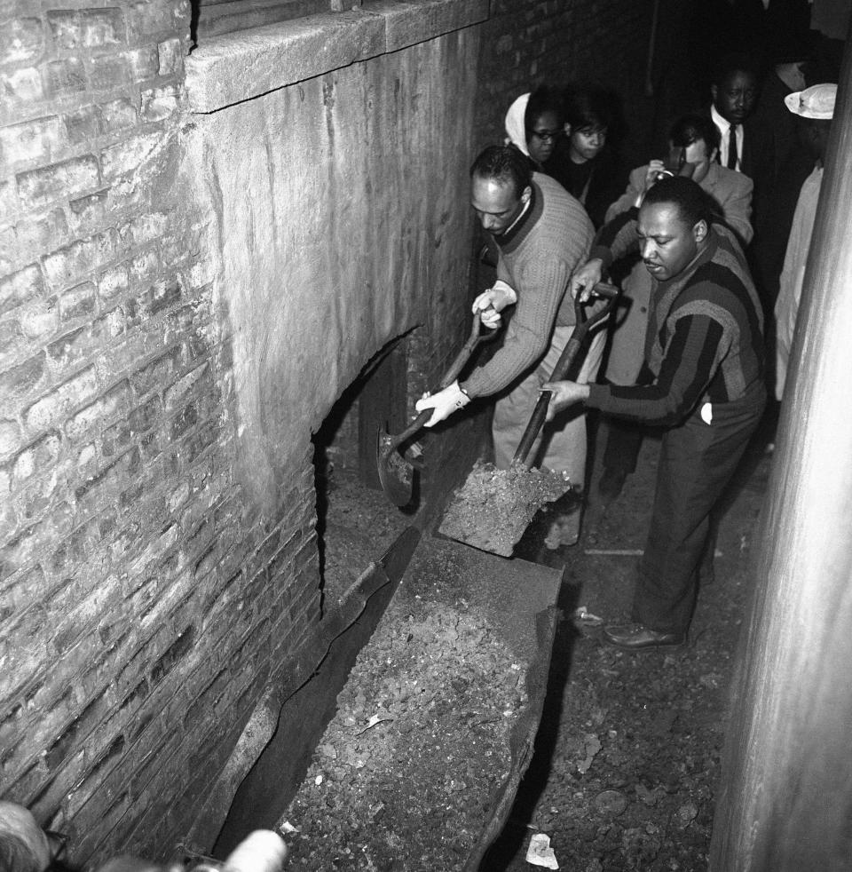 Martin Luther King attacks slum conditions at an apartment building in Chicago, Illinois on Feb. 23, 1966 where R.V. Towns lives with his wife Risoe and seven children. Al Raby, CCO, and King and several Catholic priests use shovels to clean up wheelbarrows of trash and ashes from the basement from stair steps.