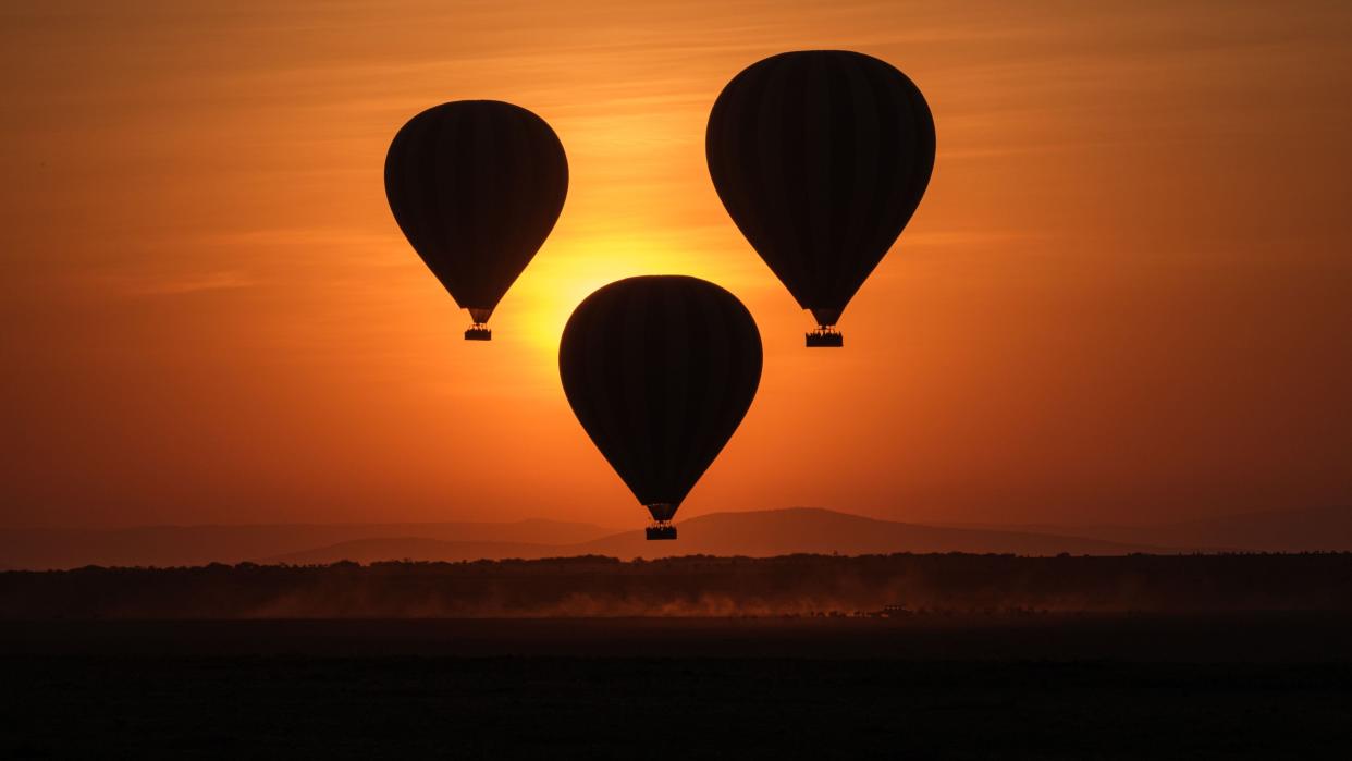 TOPSHOT - Hot-air balloons fly up with tourists at sunrise in the Masai Mara game reserve in Kenya on September 20, 2019. (Photo by Yasuyoshi CHIBA / AFP)        (Photo credit should read YASUYOSHI CHIBA/AFP/Getty Images) (Photo: YASUYOSHI CHIBA via Getty Images)