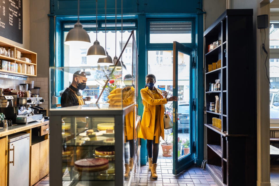 Woman entering a quaint coffee shop, with man working behind the counter