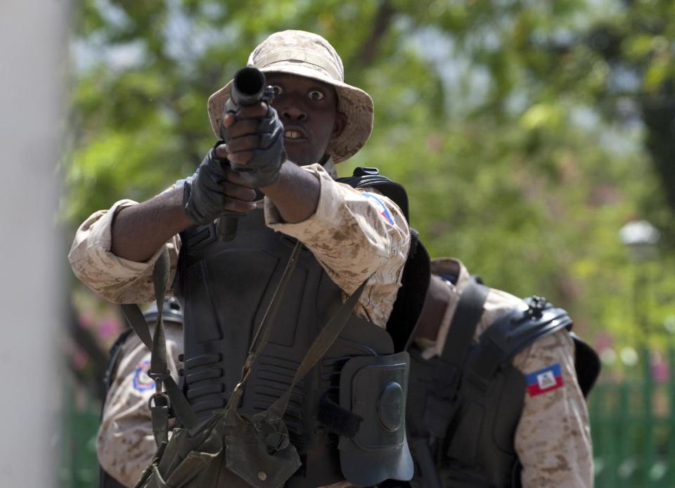 A National Police officer readies to fire tear gas at protestors during an anti-goverment protest in Port-au-Prince, Haiti, Tuesday April 15, 2014. The protesters called for the resignation of President Michel Martelly. ( AP Photo/Dieu Nalio Chery)