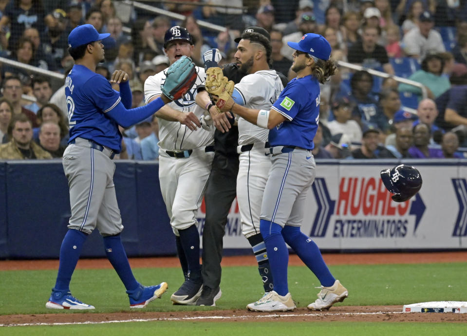 Tampa Bay Rays third base coach Brady Williams, center left, and Toronto Blue Jays shortstop Bo Bichette, right, try to break up a confrontation between Tampa Bay's Jose Caballero, center right, and Toronto Blue Jays reliever Genesis Cabrera, left, after Cabrera pushed Caballero during the seventh inning of a baseball game, Saturday, March 30, 2024, in St. Petersburg, Fla. (AP Photo/Steve Nesius)