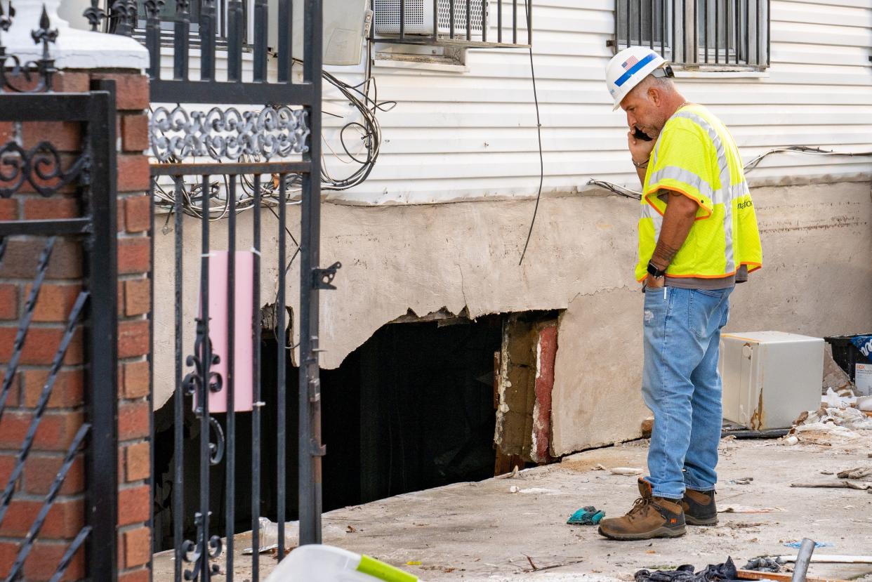 A utility worker examines the broken wall where floodwaters entered a basement apartment where two residents died on 183rd Street in Queens, New York during Storm Ida in September 2021.