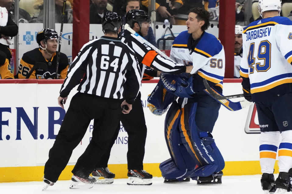 St. Louis Blues goaltender Jordan Binnington (50) is pushed away from the Pittsburgh Penguins bench by official Justin St. Pierre (12) as he is replaced in goal by Thomas Greiss during the second period of an NHL hockey game in Pittsburgh, Saturday, Dec. 3, 2022. (AP Photo/Gene J. Puskar)