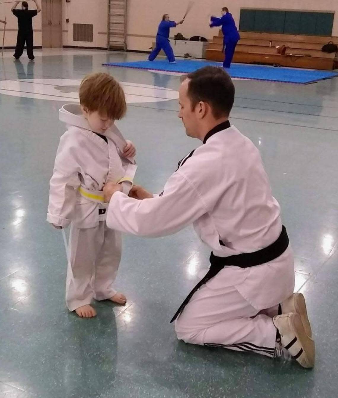 Brandon Whipple ties a new belt on his son AJ after his taekwondo test at the Osage Park Recreation Center.