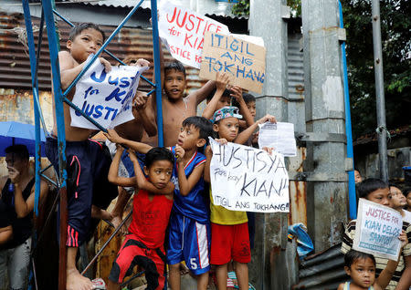 Residents hold placards near the wake of Kian Loyd delos Santos, a 17-year-old high school student, who was among the people shot dead last week in an escalation of President Rodrigo Duterte's war on drugs in Caloocan city, Metro Manila, Philippines August 21, 2017. REUTERS/Erik De Castro