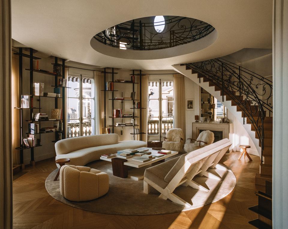 Designer Isabelle Stanislas opened the living-room ceiling to the dome above and connected them with a dramatic curving staircase. Vladimir Kagan sofa; Christian Liaigre cocktail table; Stanislas-designed bookshelves and marble sofa with cushions of a Loro Piana cashmere.