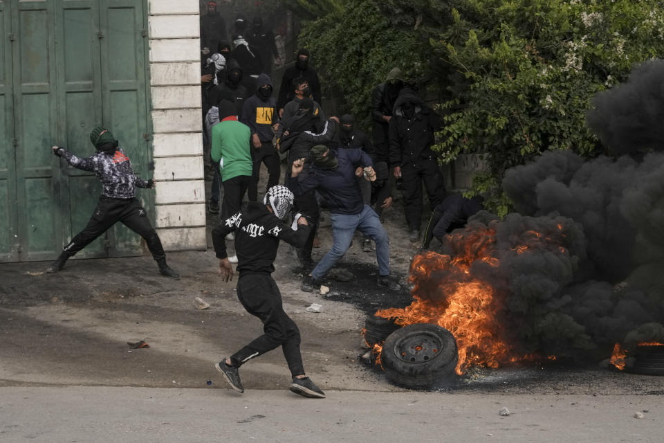 Masked Palestinians clash with Israeli security forces following the funeral of Mufid Khalil in the West Bank village of Beit Ummar, near Hebron, Tuesday, Nov. 29, 2022. Khalil was killed by Israeli fire in the occupied West Bank, the Palestinian Health Ministry said Tuesday. The Israeli military said soldiers shot at Palestinians who hurled rocks and improvised explosive devices and shot at the troops. (AP Photo/Mahmoud Illean)