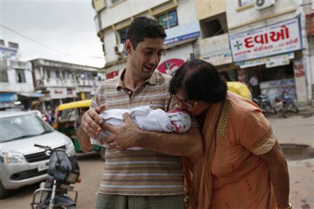 Daniele Fabbricatore, 39, holds his week-old daughter Gabriella, who is kissed by her maternal grandmother Vanita Patel, outside the Akanksha IVF centre in Anand town, about 70 km (44 miles) south of the western Indian city of Ahmedabad August 26, 2013. REUTERS/Mansi Thapliyal