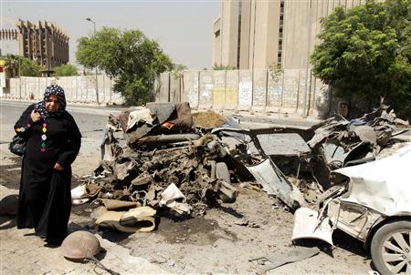 A woman walks past the site of a car bomb attack in Baghdad, September 18, 2013. REUTERS/Ahmed Saad