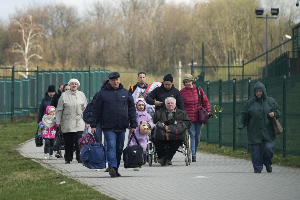 Refugees walk after fleeing the war from neighbouring Ukraine at the border crossing in Medyka, southeastern Poland, Monday, April 11, 2022. (AP Photo/Sergei Grits)