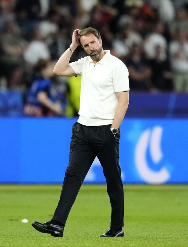 Gareth Southgate walks on a pitch and scratches his head