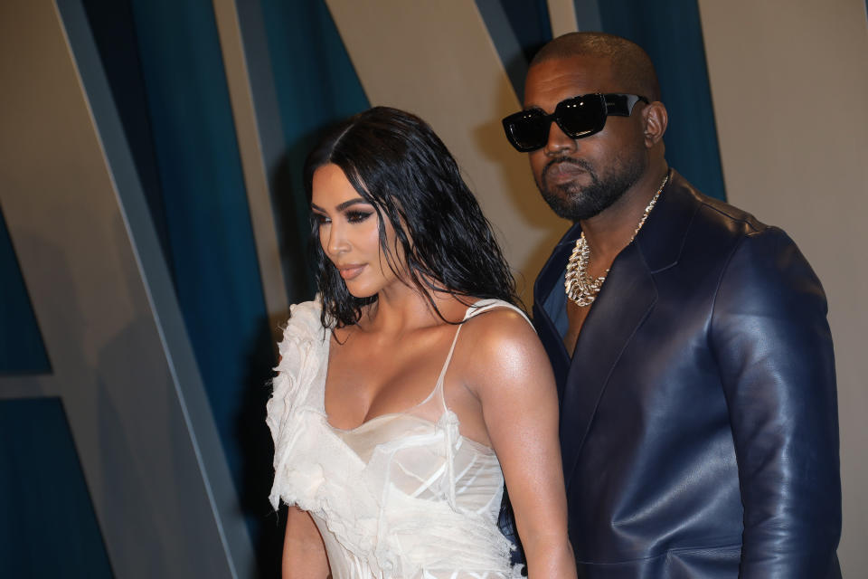Photo of Kim Kardashian in a white gauzy dress with Kanye West in a leather suit and sunglasses