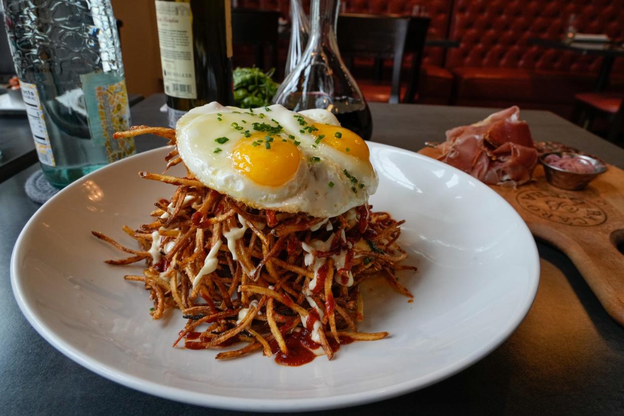 Huevos Cabreados has fried eggs atop a bowl of thin shoestring French fries.