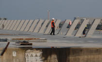 A worker stands on the construction site of the project in Venice, Italy, Friday, Nov. 29, 2019. The system of moveable under water barriers, dubbed Moses, has been beset by corruption, cost overruns and delays. Projected at 1.8 billion euros and to be completed by 2011, the project has cost 5.5 billion euros and won’t be operational before the end of 2021. (AP Photo/Antonio Calanni)