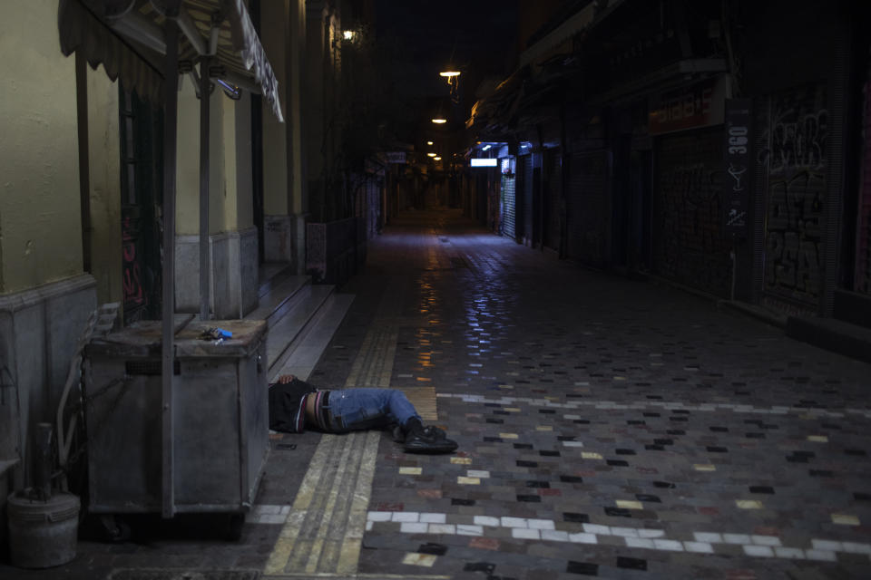 A man sleeps on a street outside shuttered shops in the Monastiraki district of Athens during lockdown measures to prevent the spread of the coronavirus, on Monday, April 27, 2020. (AP Photo/Petros Giannakouris)