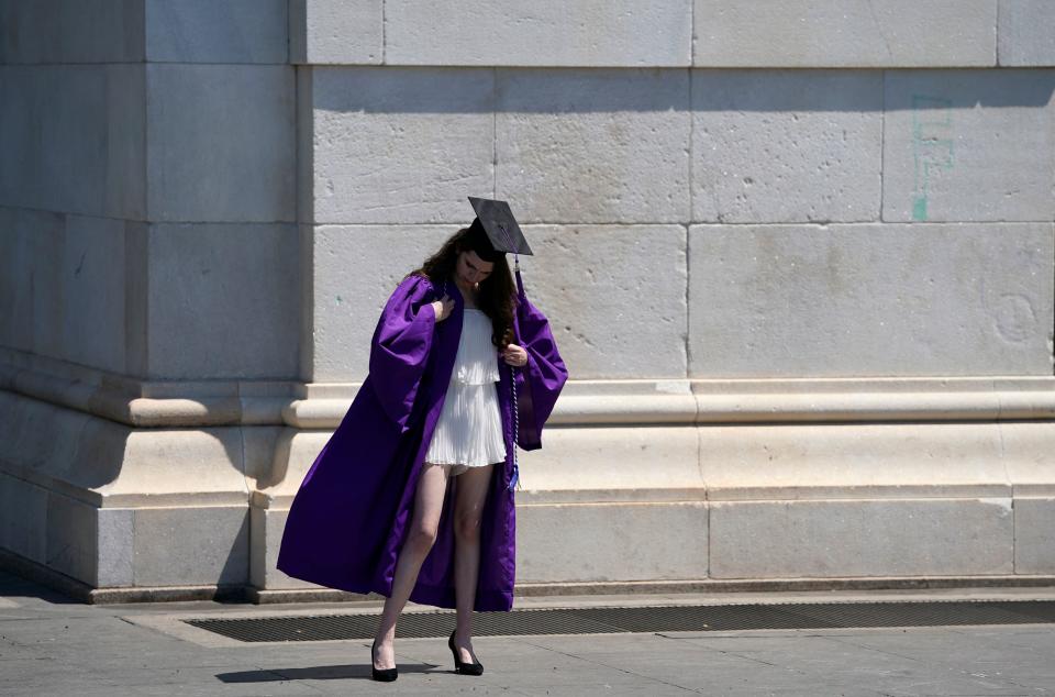 A graduate fixes her outfit before getting her picture taken in Washington Square Park, New York on May 19, 2021. (Photo by TIMOTHY A. CLARY / AFP) 