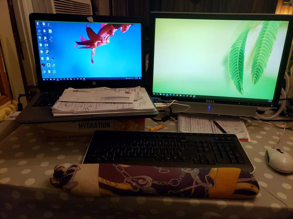 To make her new office more ergonomic, systems analyst Angie Wilbur used an old shampoo box for a monitor riser and a wrist rest made from socks and rice on her dining room table. (Photo: Angie Wilbur)