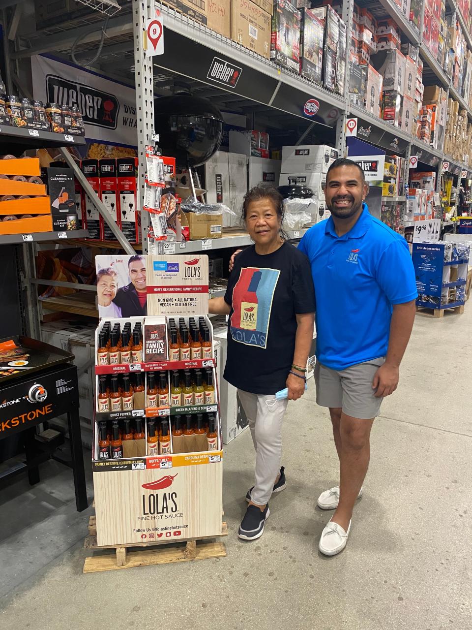 Taufeek and Carmelita Shah, the mother-and-son team behind Lola's Fine Hot Sauce, pose for a picture next to their display in Lowe's.