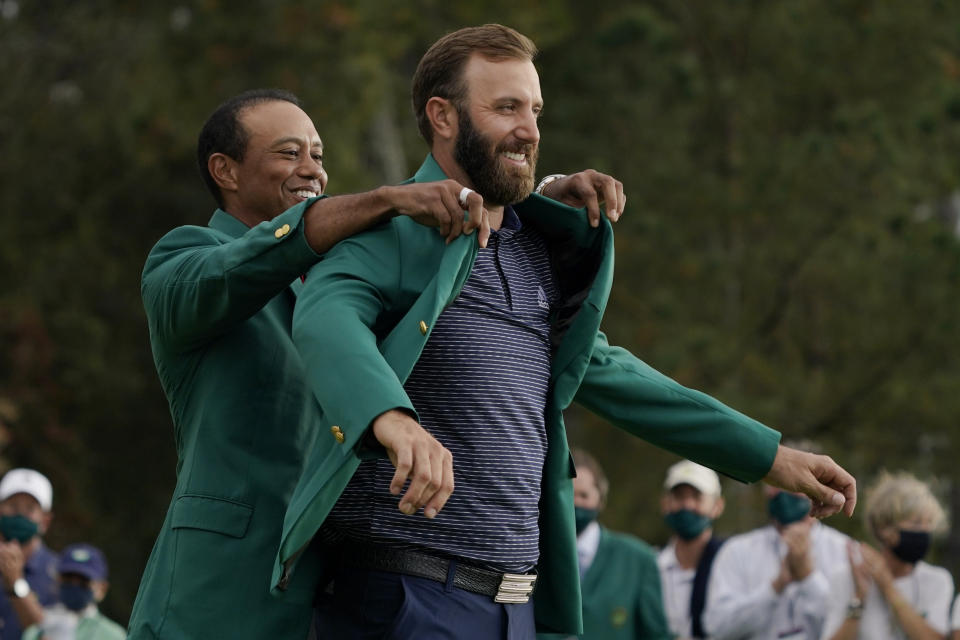 FILE - Tiger Woods helps Masters' champion Dustin Johnson with his green jacket after his victory at the Masters golf tournament in Augusta, Ga., in this Sunday, Nov. 15, 2020, file photo. It will be 144 days from when Tiger Woods helped Johnson into his green jacket until Johnson tees off in the opening round in his bid to join Woods, Nick Faldo and Jack Nicklaus as the only repeat winners at Augusta. (AP Photo/Charlie Riedel, File)