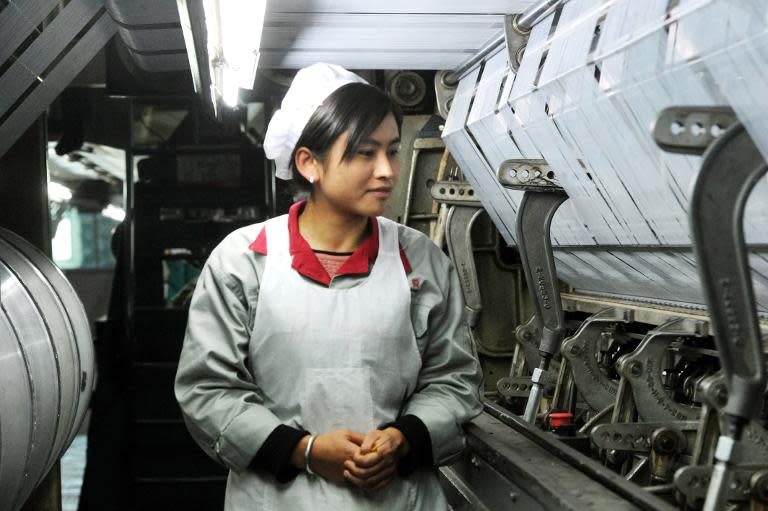 A worker checks a machine making blankets for exports at a factory in Yiwu, east China's Zhejiang province, on January 12, 2015