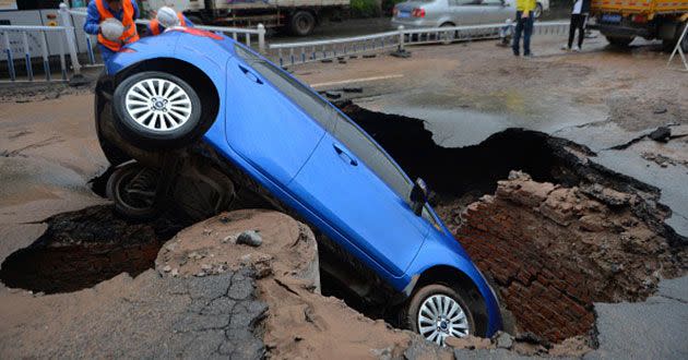 A car hangs precariously over a hole in the road in China. Source: Getty