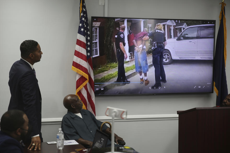 Attorney Justin Bamberg, left and and his client Clarence Gailyard, right, watch police body camera video of an officer stomping Gailyard in the neck as Bamberg holds a news conference on Tuesday, Aug. 3, 2021 in Orangeburg, South Carolina. Orangeburg Public Safety officer David Lance Dukes was fired and charged with a felony after the July 26 incident. (AP Photo/Jeffrey Collins)