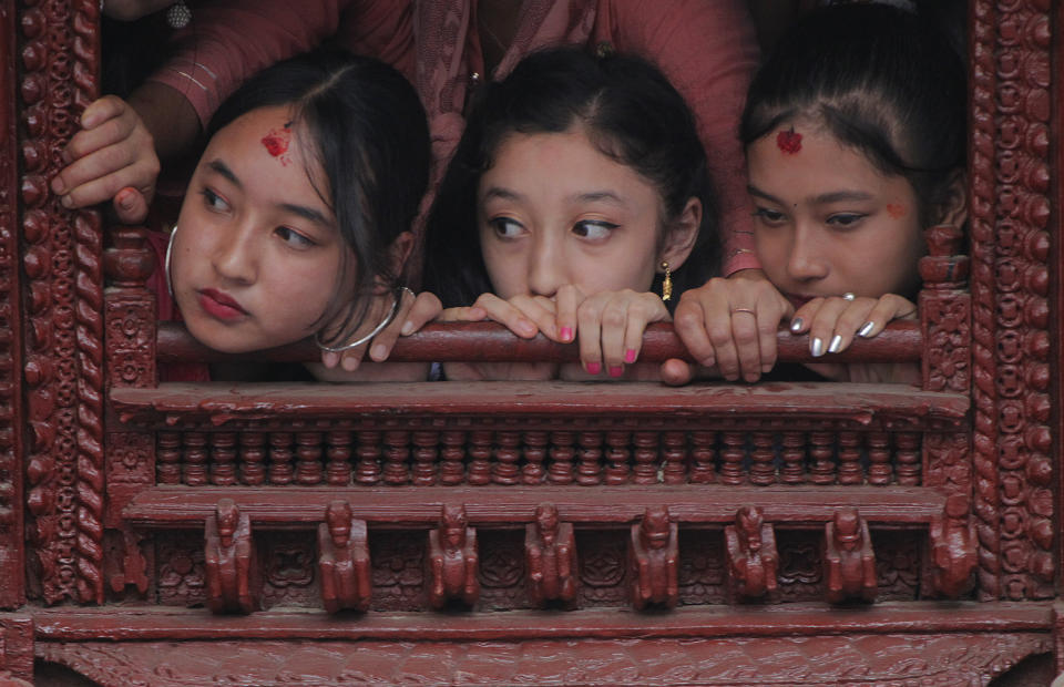 A former living goddess Kumari, middle, watches the Indra Jatra festival, an eight-day festival that honors Indra, the Hindu god of rain, in Kathmandu, Nepal, Friday, Sept. 13, 2019. The girl child revered as the Living Goddess Kumari is pulled around Kathmandu in a wooden chariot, families gather for feasts and at shrines to light incense for the dead, and men and boys in colorful masks and gowns representing Hindu deities dance to the beat of traditional music and devotees' drums, drawing tens of thousands of spectators to the city's old streets. (AP Photo/Niranjan Shrestha)