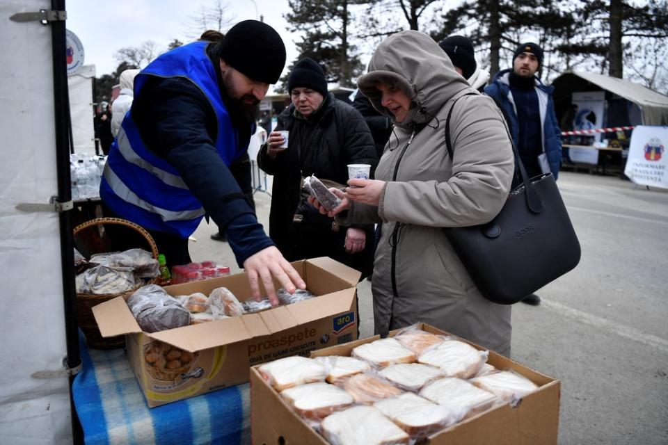 Father Mikhail offers Ukrainian refugees food at their hospitality tent in Siret (Reuters)