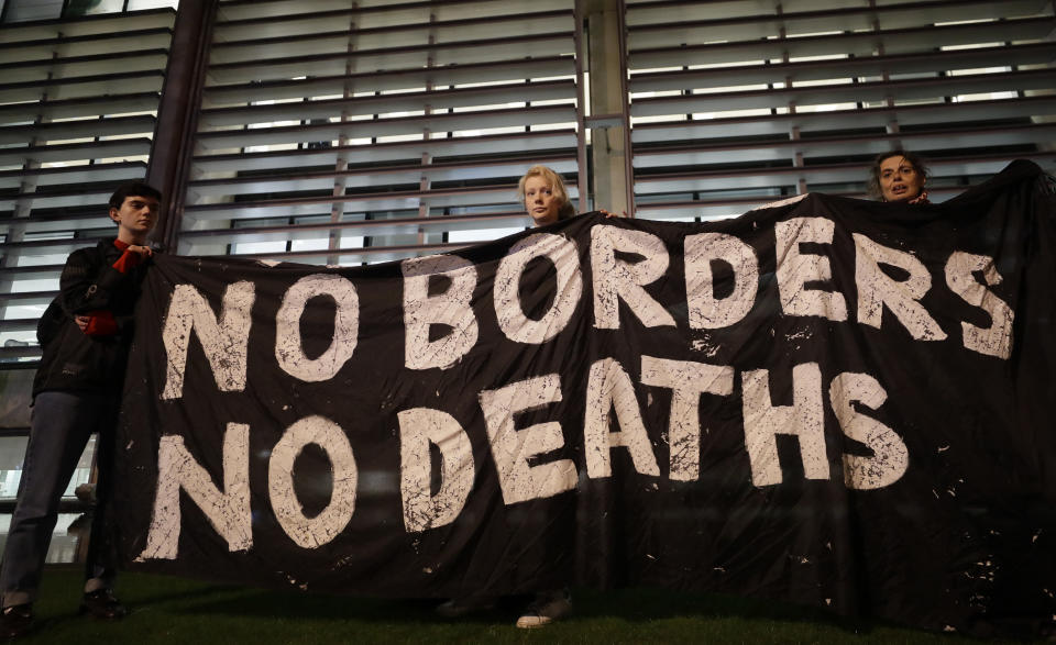 Demonstrators hold a banner during a vigil for the 39 lorry victims, outside the Home Office in London, Thursday, Oct. 24, 2019. Authorities found 39 people dead in a truck in an industrial park in England on Wednesday and arrested the driver on suspicion of murder in one of Britain's worst human-smuggling tragedies. (AP Photo/Kirsty Wigglesworth)
