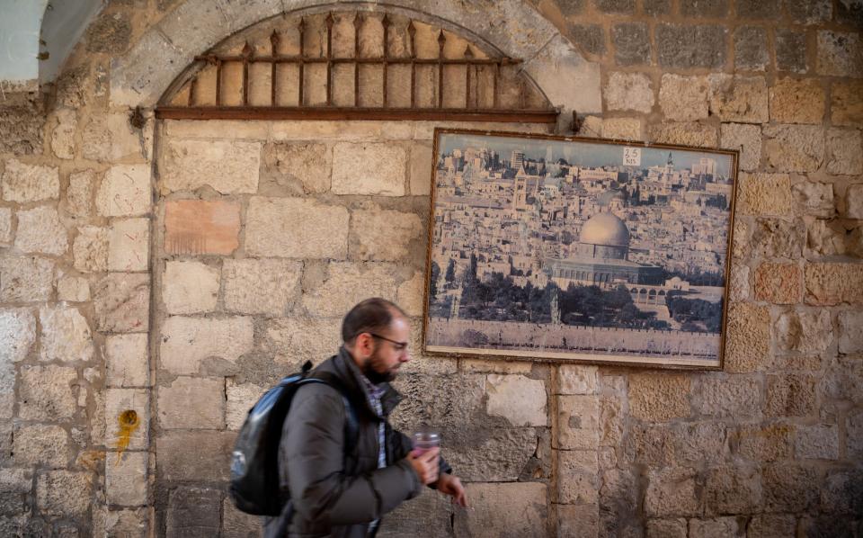 A person runs passed a frame with a picture of the Dome of the Rock hanging on a wall inside JerusalemÕs Old City.