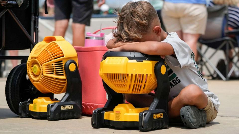 PHOTO: Braxton Hicks, 7, of Livingston, Texas, holds his face to a portable fan to cool off during the DYB, formerly Dixie Youth Baseball, Little League tournament in Ruston, La., Aug. 9, 2023. (Gerald Herbert/AP)