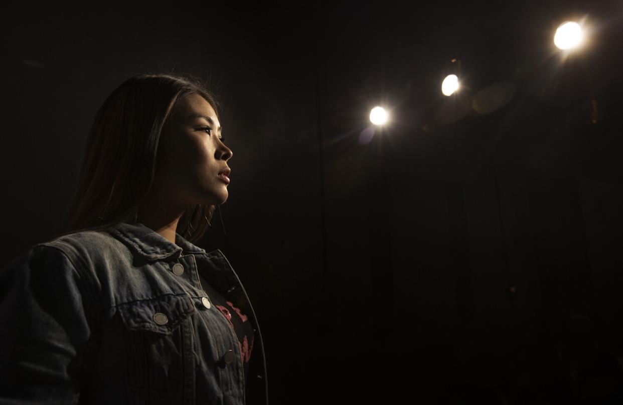 A woman in dim lighting looks serious