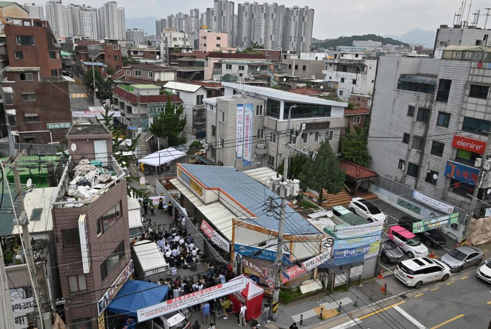 TOPSHOT - Government officials wearing protective clothing stand under a white tent (centre L) to restrict access to the Sarang Jeil Church while the church's lawyer holds a press conference on its latest COVID-19 cluster infection near the church in Seoul on August 17, 2020. - Thousands of Protestant church members in Seoul have been asked to quarantine, South Korean authorities said on August 17, as the country battles virus clusters linked to religious groups. A total of 315 cases linked to the Sarang Jeil Church had been confirmed so far, officials said, making it one of the biggest clusters so far, and around 3,400 members of the congregation had been asked to quarantine. (Photo by Jung Yeon-je / AFP) (Photo by JUNG YEON-JE/AFP via Getty Images)