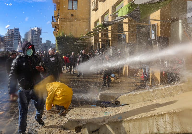 Demonstrators are sprayed with a water cannon during a protest seeking to prevent MPs and government officials from reaching the parliament for a vote of confidence, in Beirut