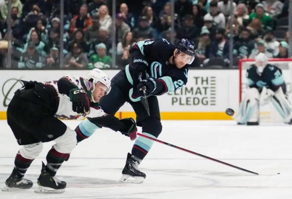 Seattle Kraken defenseman Carson Soucy sends the puck past Arizona Coyotes right wing Christian Fischer, left, during the first period of an NHL game Thursday, April 6, 2023, at Climate Pledge Arena. The Kraken won 4-2 to clinch their first appearance in the Stanley Cup Playoffs.