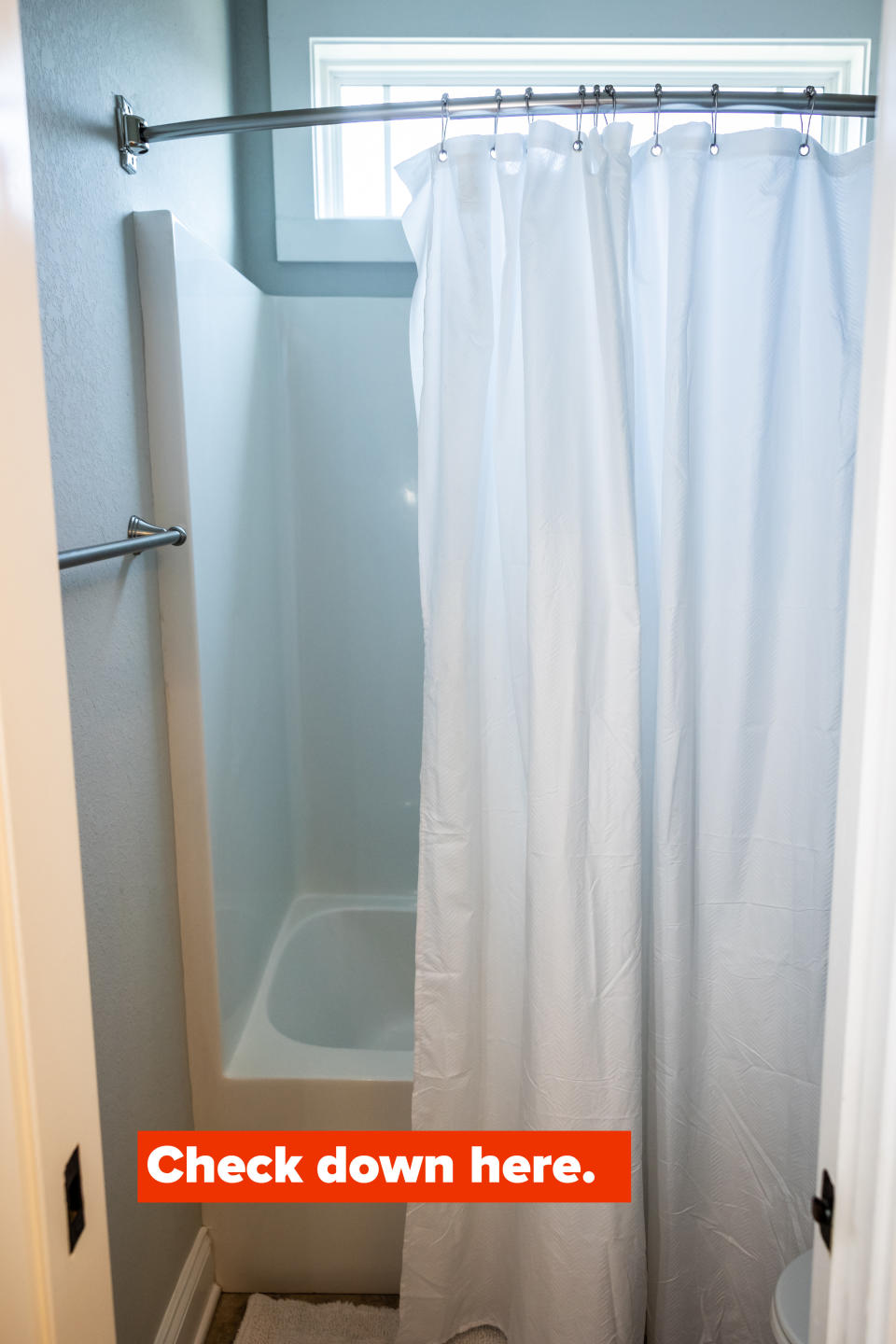 A generic looking shower curtain pulled partially open revealing part of a bathtub