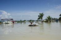 A flood-affected resident uses a make-shift raft to travel through floodwaters in Kalay, upper Myanmar's Sagaing region on August 3, 2015