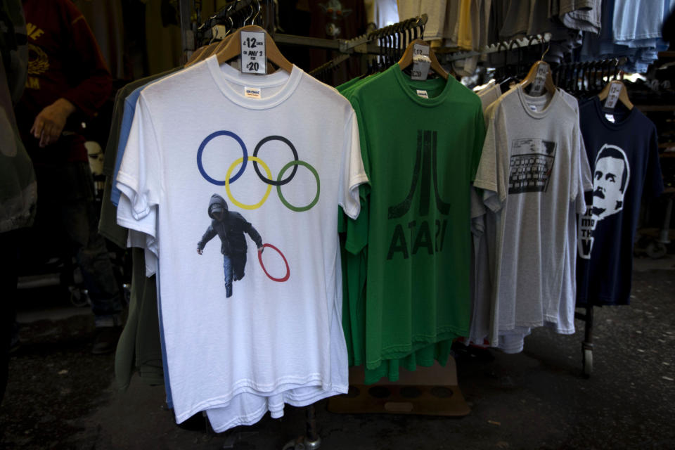 In this photo taken Monday, July 16, 2012, a t-shirt depicting a rioter holding an Olympic ring is displayed on sale in a London market. The guardians of the games are vigilant about protecting the integrity - and the commercial clout - of the Olympic brand. But even they can't stop the irreverent spirit of artists and craftspeople, who have responded to the games with a cheeky mix of celebration, skepticism and satire. (AP Photo/Matt Dunham)