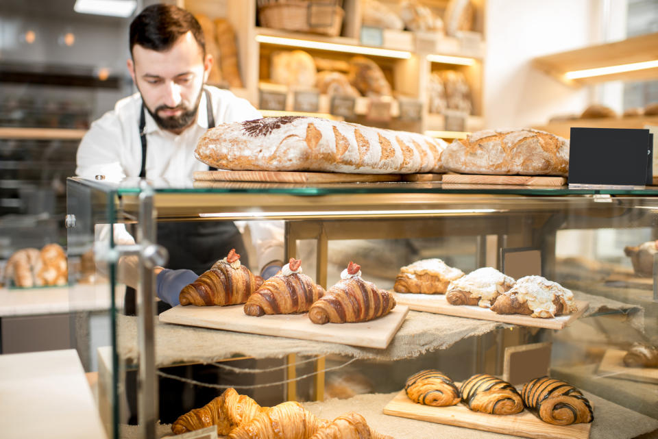 Seller putting delicious croissants on the store showcase of the bakery house