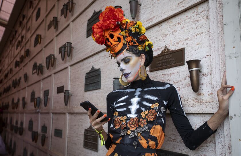 • LOS ANGELES, CALIF. - NOVEMBER 02: Arnaldo Garcia "popcorn" checks his phone during Hollywood Forever's 20th annual Dia de los Muertos celebration in Los Angeles, Calif. on Saturday, Nov. 2, 2019. This year our guiding theme is the Monarch Butterfly and its winter home the Mexican state of Michoacán. Michoacán is also one of the two cultural heartlands in Mexico where the ancient traditions of Dia de los Muertos have been celebrated the longest and most vibrantly. (Francine Orr / Los Angeles Times)