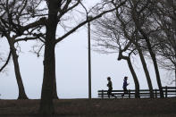 Two runners get in their last legs of exercise before a Chicago police officer notifies them that the trails along Lake Michigan are closed in an effort to limit the spread of COVID-19 infections, Thursday, March 26, 2020, in Chicago. The new coronavirus causes mild or moderate symptoms for most people, but for some, especially older adults and people with existing health problems, it can cause more severe illness or death. (AP Photo/Charles Rex Arbogast)