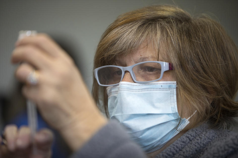 Sue Mason fills a syringe with a dose of the Moderna COVID-19 vaccine inside of the pharmacy station at the Hamilton County Health Department's new COVID Vaccination POD at the CARTA Bus Terminal on Thursday, Jan. 28, 2021 in Chattanooga, Tenn. (Troy Stolt/Chattanooga Times Free Press via AP)