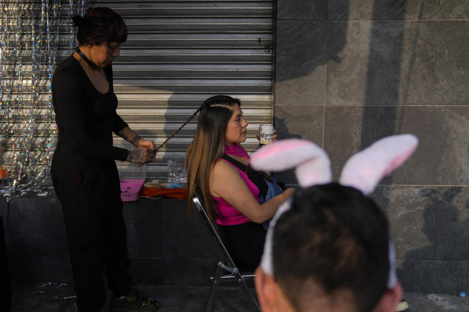 Una mujer se peina antes de entrar al concierto de Bad Bunny en el Estadio Azteca de la Ciudad de México el viernes 9 de diciembre de 2022. (Foto AP/Eduardo Verdugo)
