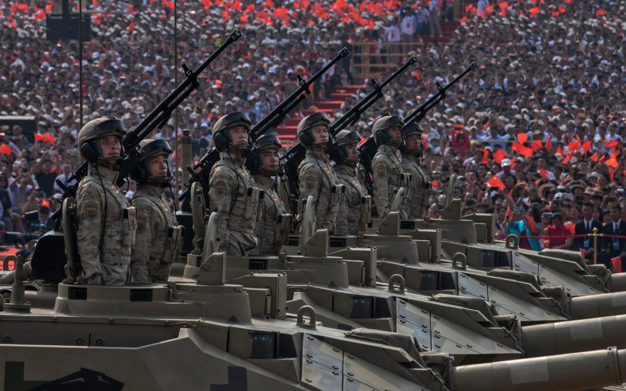 Chinese soldiers ride atop tanks as they drive in a parade - Getty