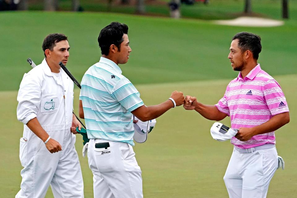 Hideki Matsuyama and Xander Schauffele fist-bump on the 18th green after completing their round Saturday at the Masters.