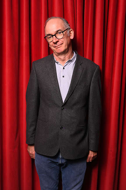 Paul Ritter stands in front of red curtain for Friday Night Dinner launch