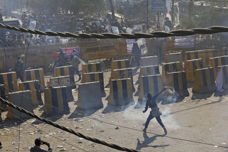 FILE - In this Friday, Nov. 27, 2020, file photo, a protesting farmer throws back a tear gas shells past concrete road blocks set up by policemen, at the border between Delhi and Haryana state. Prime Minister Narendra Modi's government also initially tried to discredit the farmers — who happen to be largely Sikh because of the demographics of the agricultural powerhouse states — by dismissing their concerns as motivated by religious nationalism.But such allegations appear to have backfired, further angering the farmers, many of whom serve in the Indian army, police and civil service. Since then, common citizens also joined them and the protests have gathered strength. (AP Photo/Altaf Qadri, File)